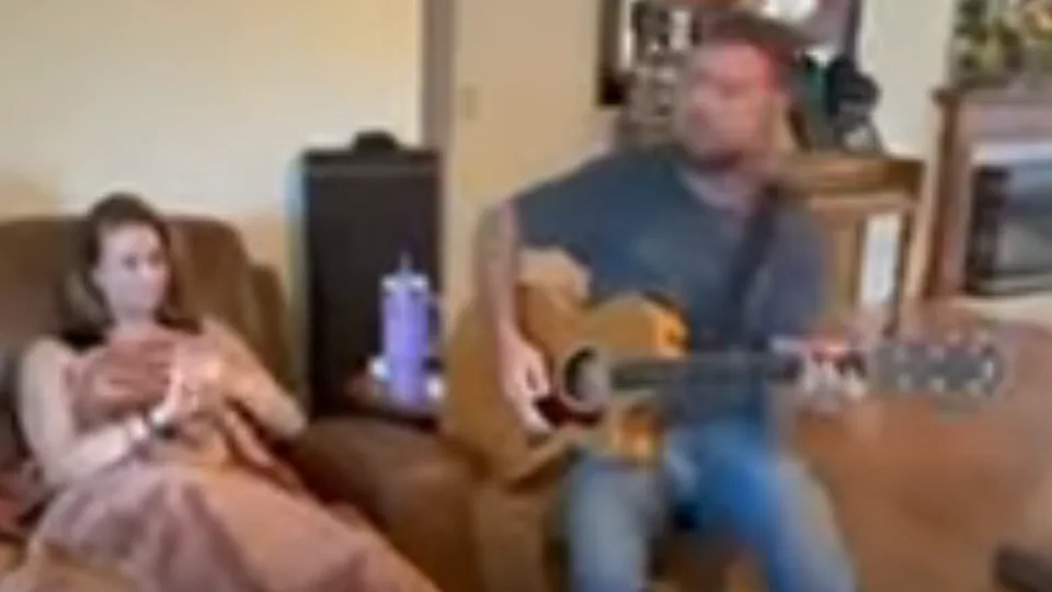Jon playing acoustic guitar in a living room