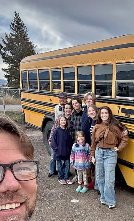 Jon with the family and a yellow school bus behind him