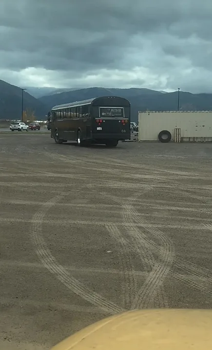 A black bus parked in a field under a cloudy sky